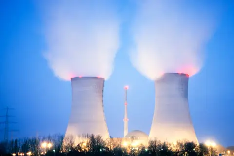 Dwie chłodnie kominowe elektrowni atomowej w Polsce wydzielają parę. W tle widać kopułę reaktora i wieżę.