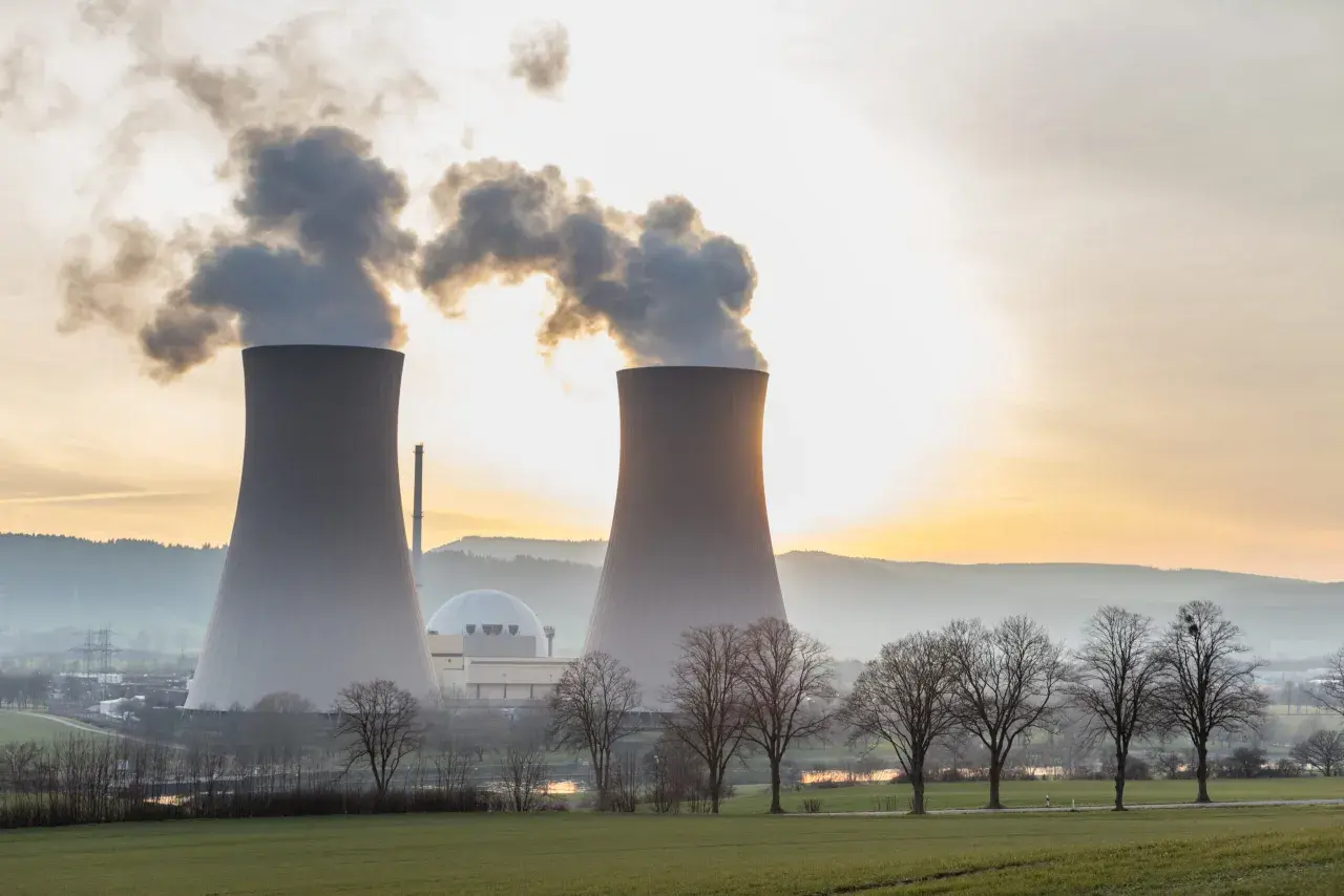 Dwie chłodnie kominowe elektrowni atomowej na tle zachodzącego słońca. Warto wiedzieć, ile prądu produkuje elektrownia atomowa.