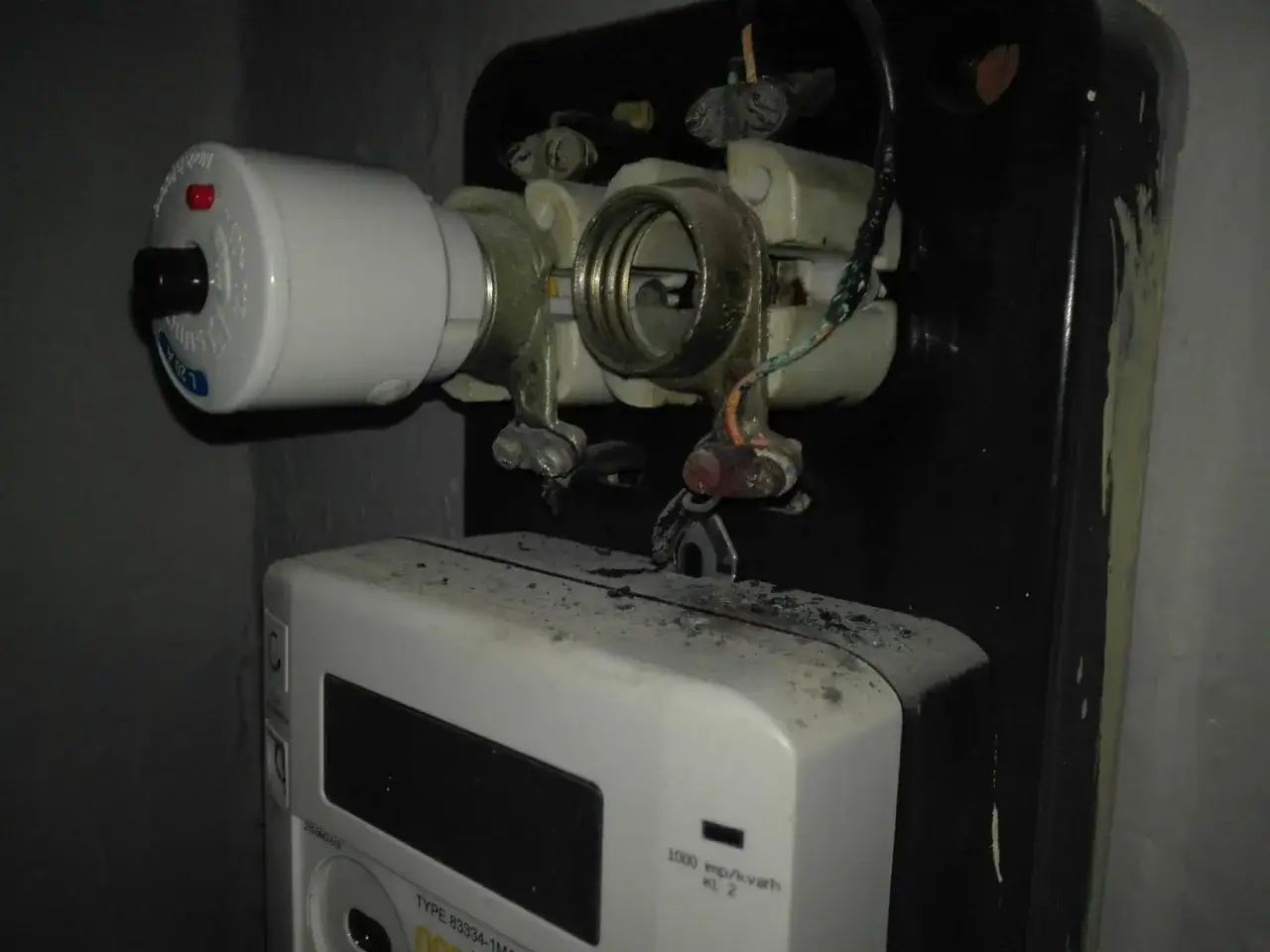 Widok na skrzynkę z bezpiecznikami i licznikiem energii elektrycznej. Pokazuje, jak wymienić bezpiecznik w skrzynce, gdy jest uszkodzony.